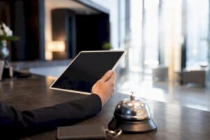 Ein Hotelmitarbeiter hält ein Tablet am Empfangstresen in den Händen.